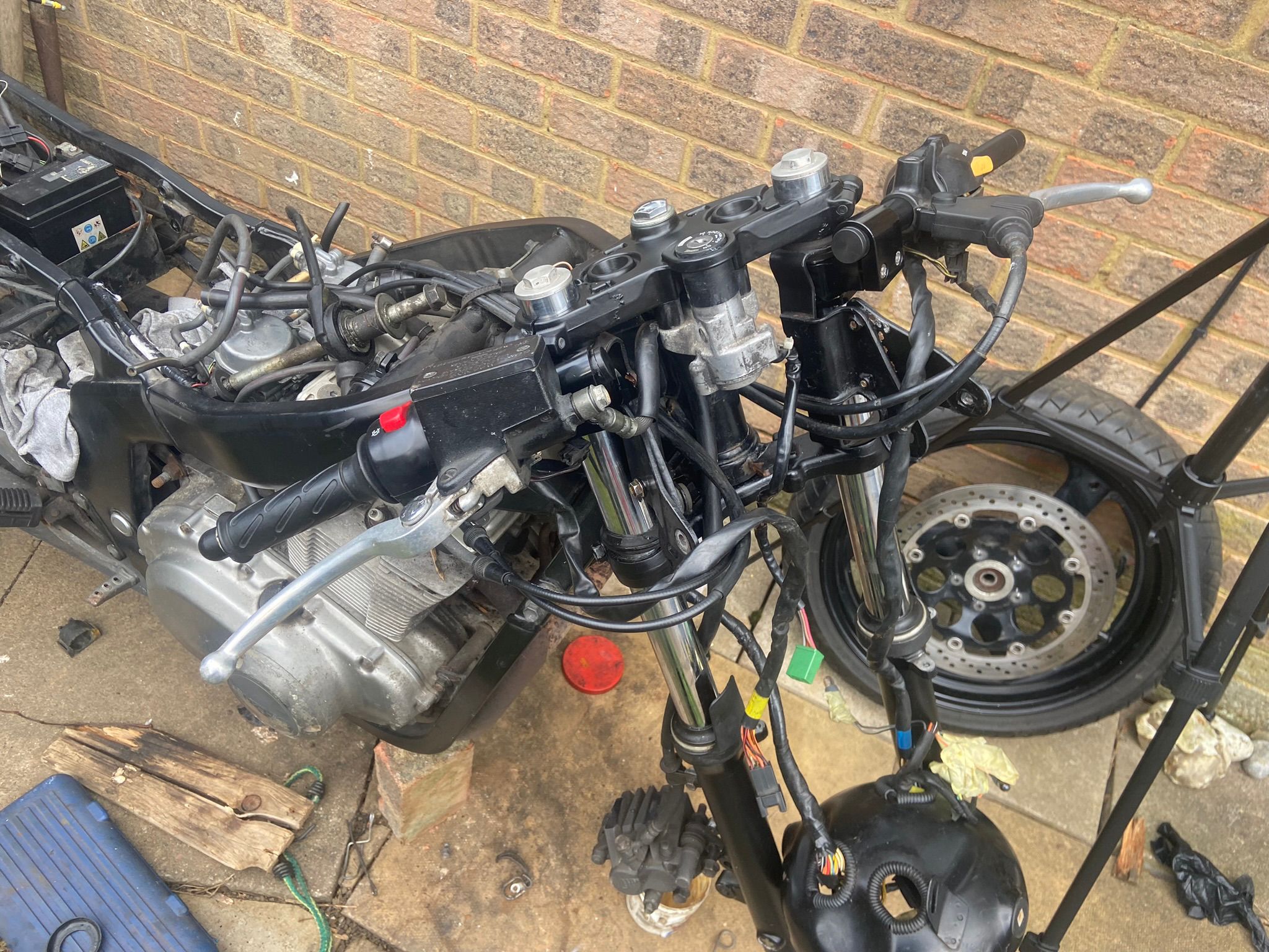 Suzuki GS500F completely stripped down – front end apart, engine visible, wheel off during the cafe racer rebuild