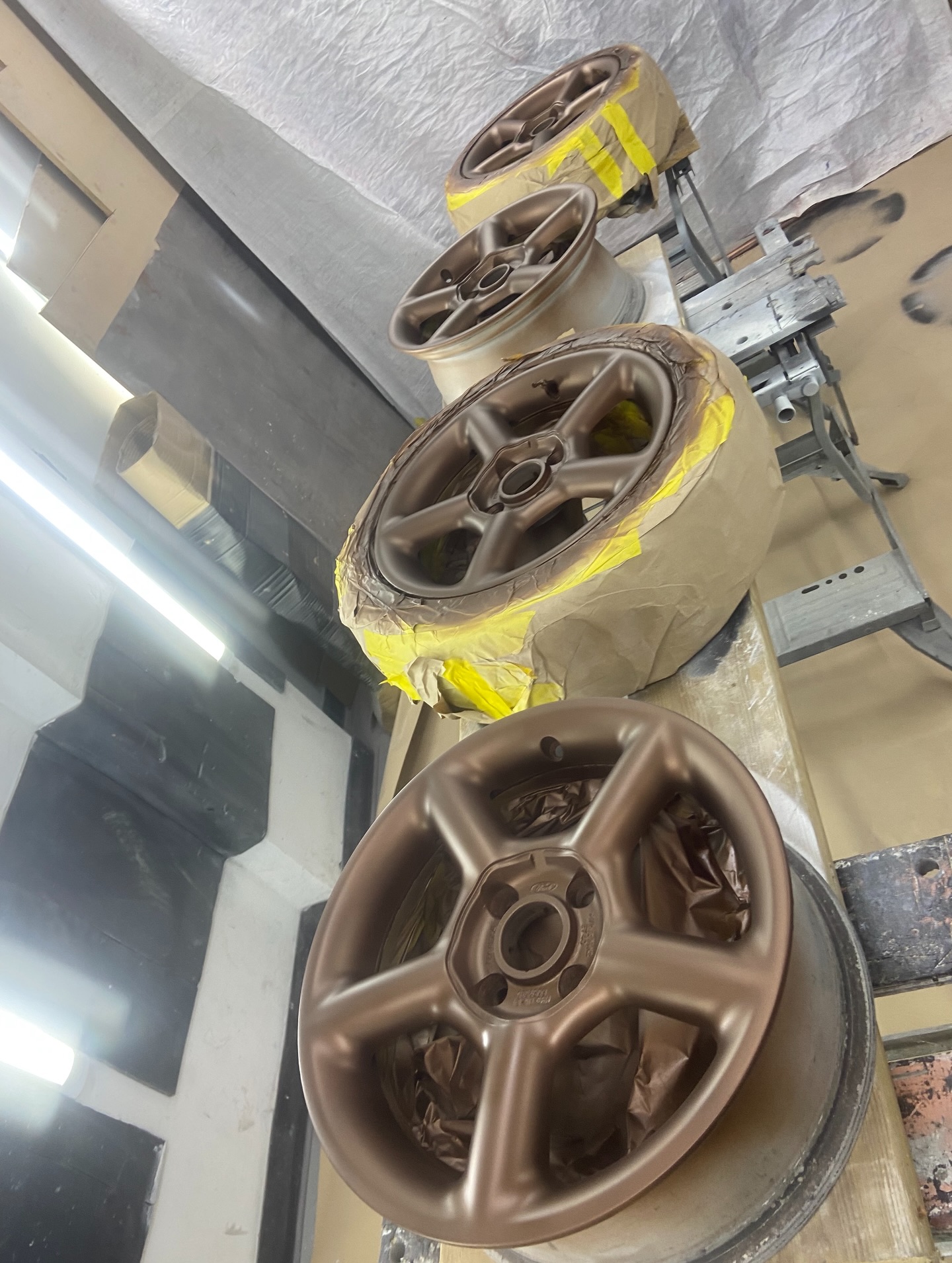 Ford Mondeo alloy wheels being sprayed bronze in the spray booth