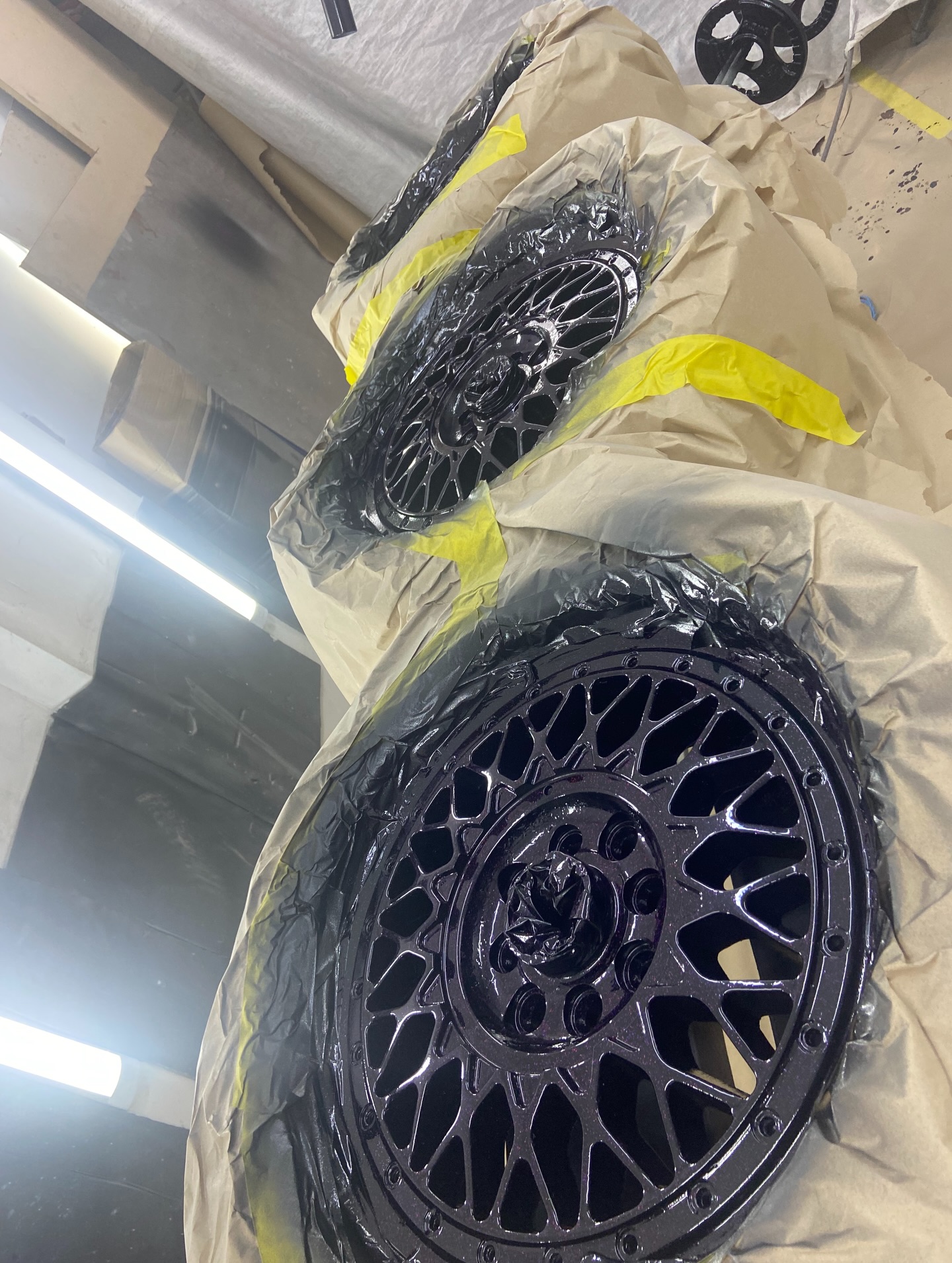 BBS-style mesh alloy wheels freshly sprayed rainbow glitter in spray booth