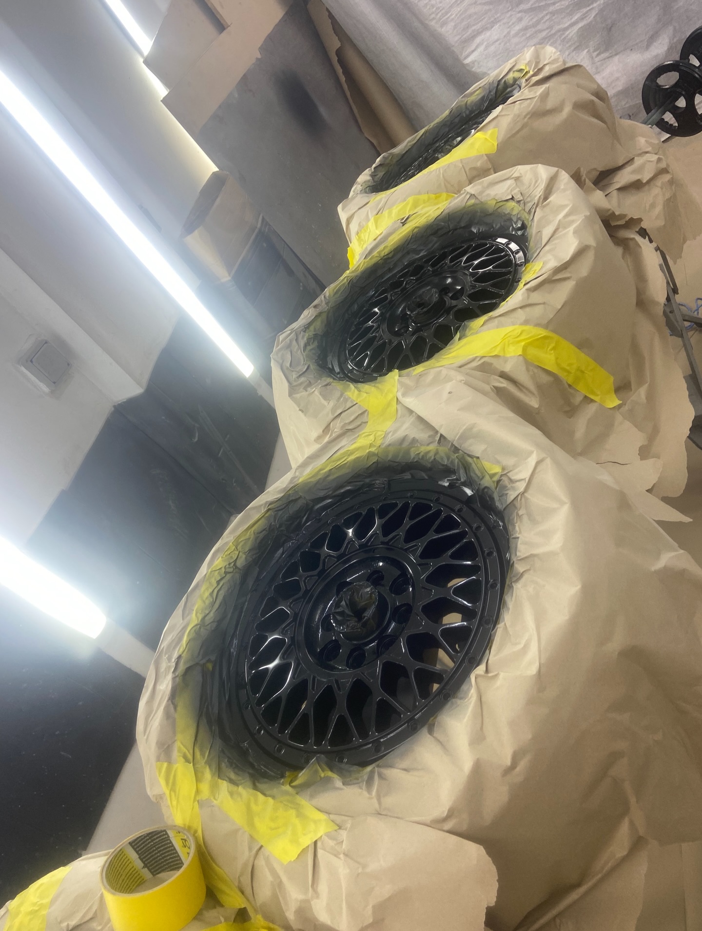 Alloy wheels masked with tape and paper, ready for spraying with tyres still fitted