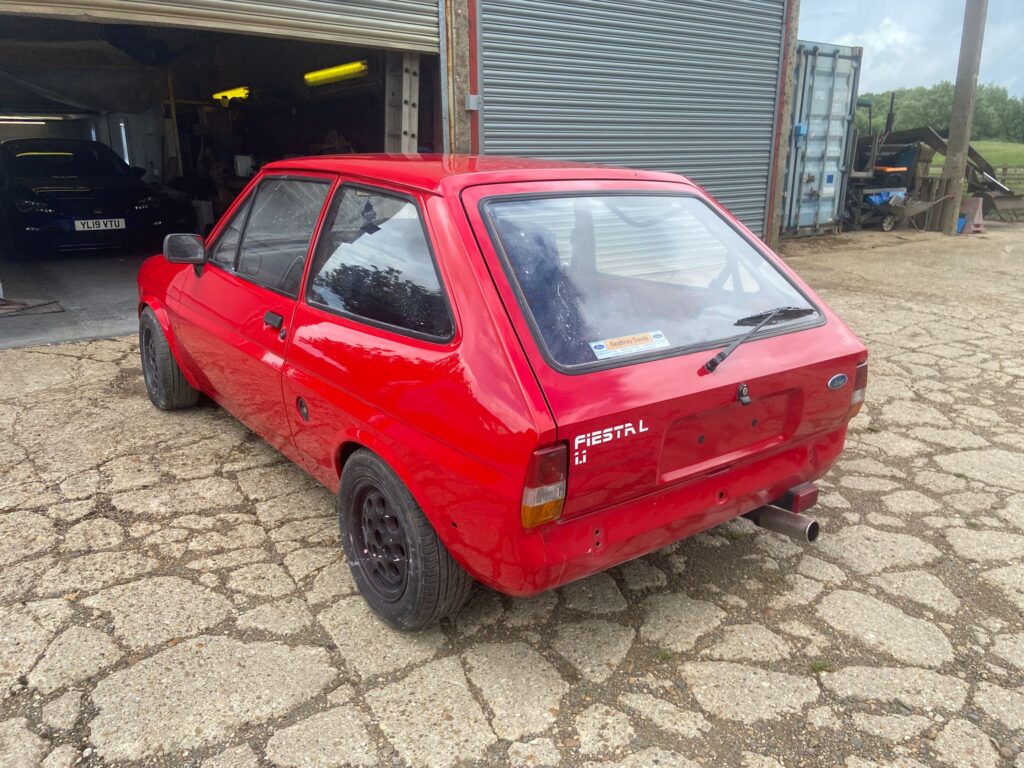 Red Ford Fiesta Mk2 rear three-quarter view after respray outside the Top Touch Coachworks workshop near Milton Keynes