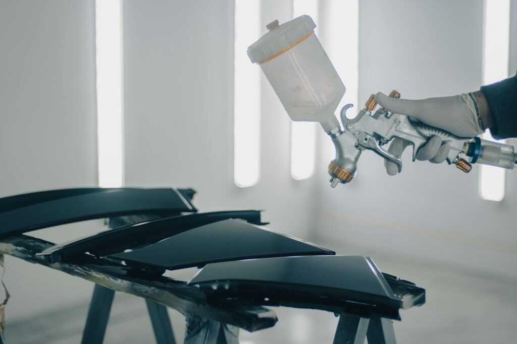 Car body panel being spray-painted in an automotive workshop