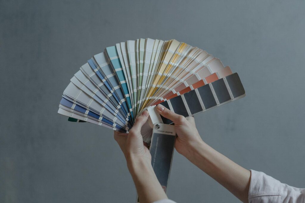 Hand holding a fan of paint colour swatches for matching