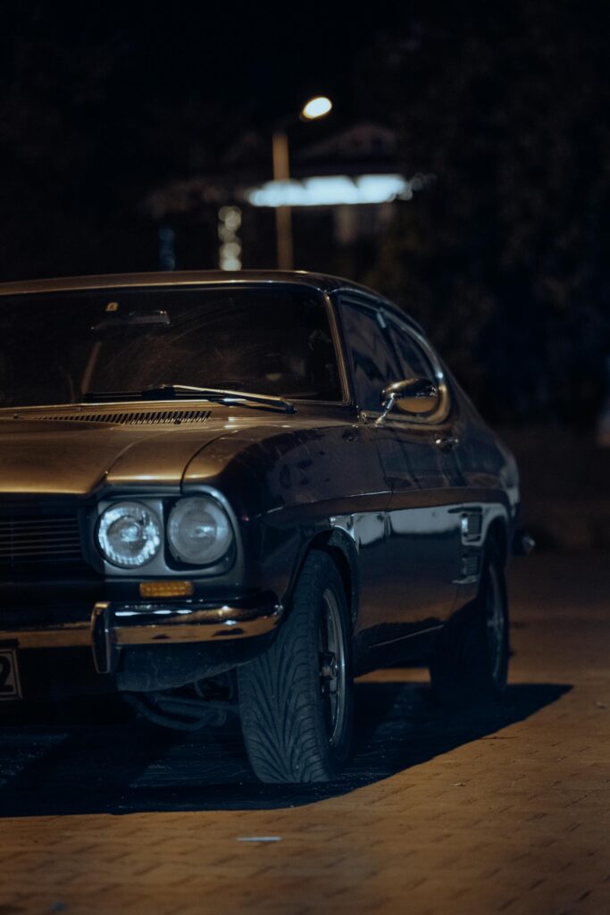 Dark Ford Capri Mk3 parked under streetlights at night, atmospheric urban setting