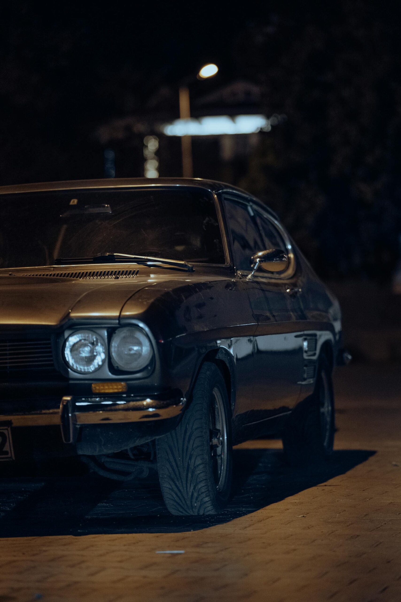 Dark Ford Capri Mk3 parked under streetlights at night, atmospheric urban setting